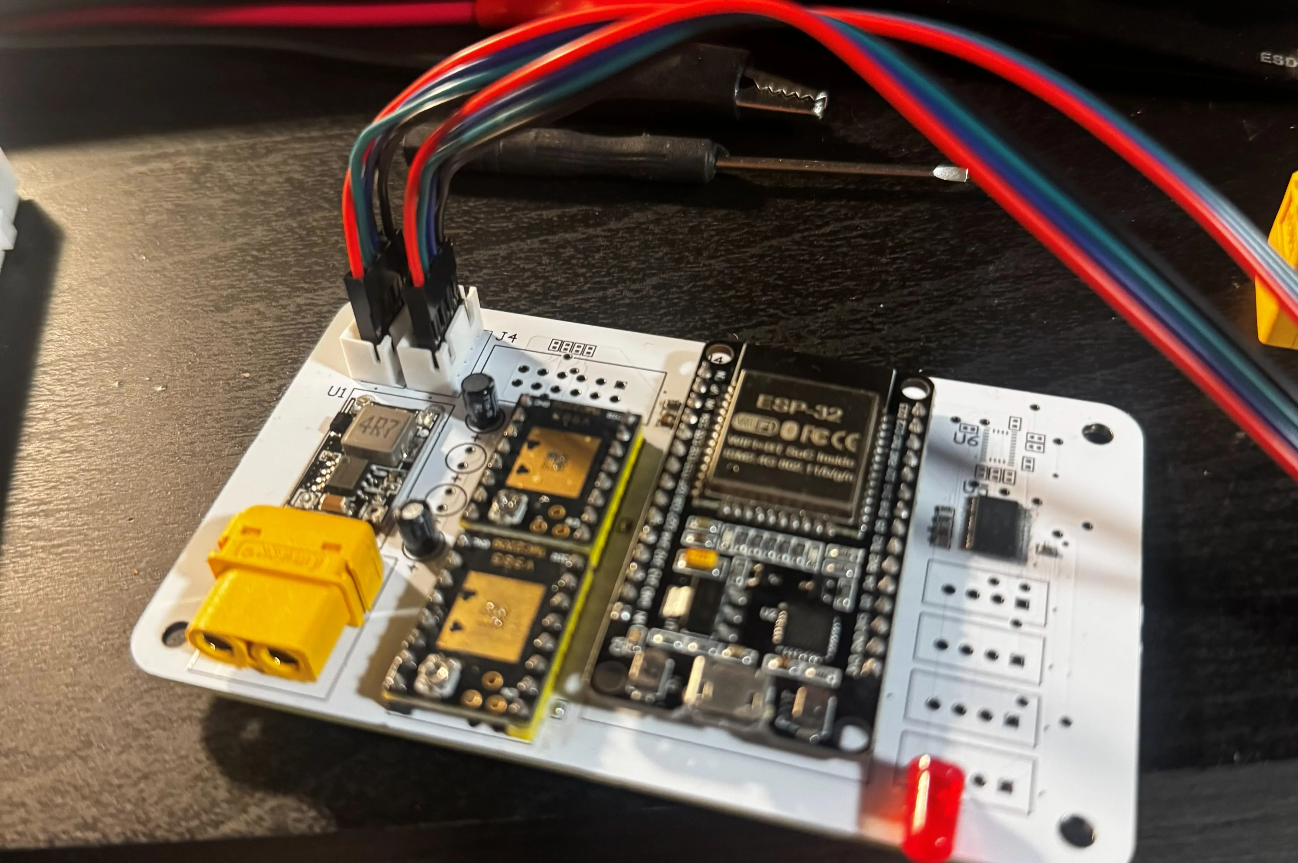 A close-up of the populated control board — the ESP32 module, two TMC2209 stepper drivers on gold thermal pads, a buck regulator and an XT-style power connector, with motor leads plugged in.
