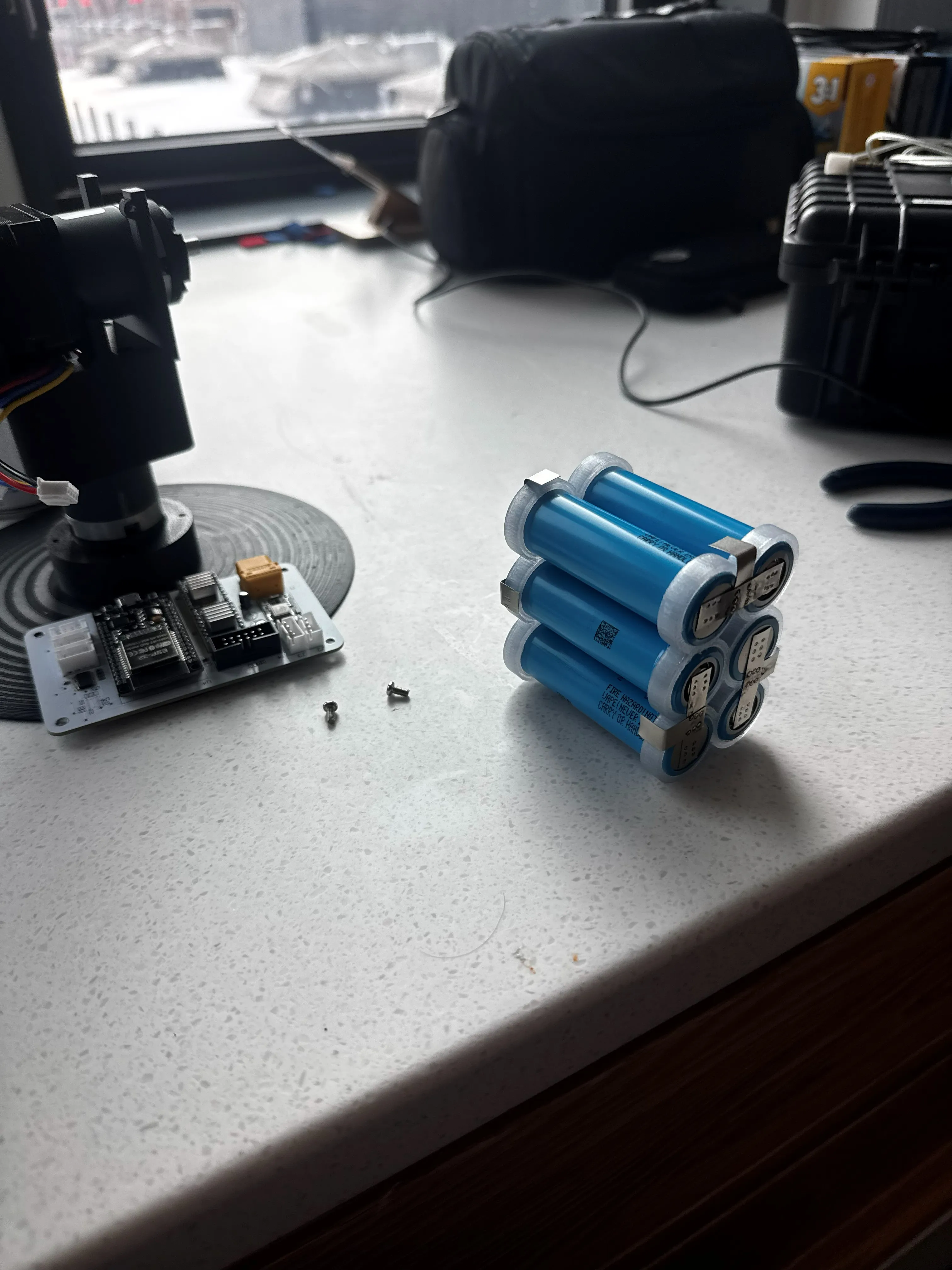 V2 build — the azimuth turntable and 3D-printed bearing, the assembled control board, and the spot-welded 21700 pack on the bench.