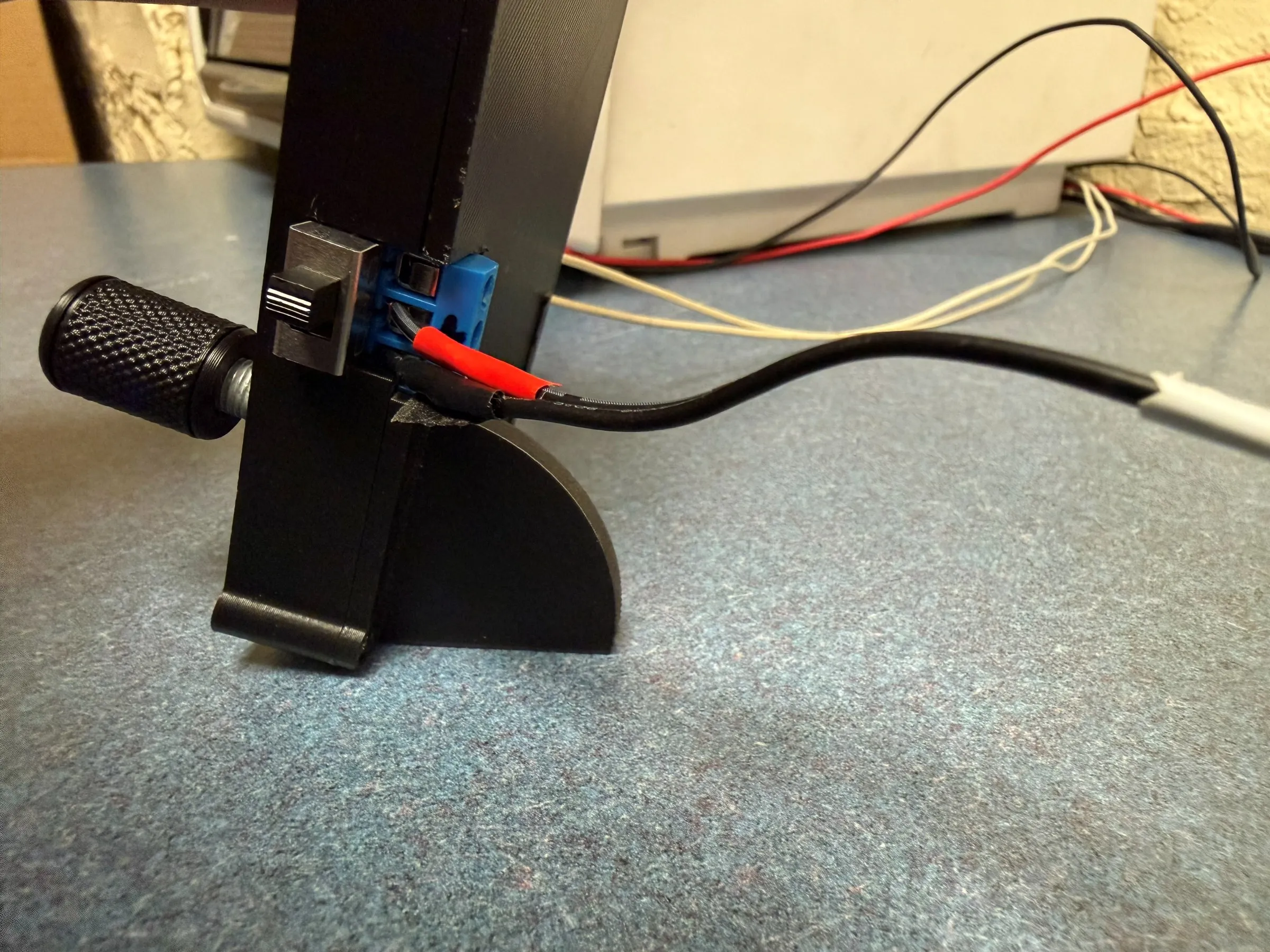 Close-up of the printed controller enclosure showing the knurled rotary encoder, rocker switch, blue screw terminals and the strain-relieved mains cable.