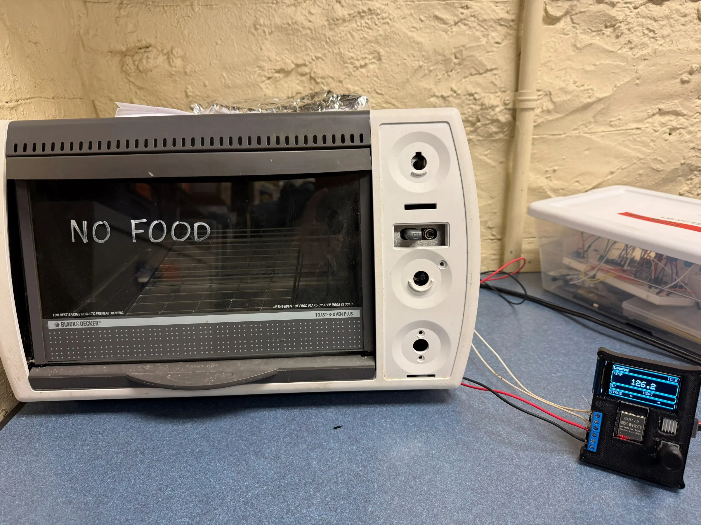 A Black & Decker Toast-R-Oven Plus with NO FOOD written on the glass door, wired to a black 3D-printed controller box whose LCD reads 126.2 degrees, stage HEAT, on the Leaded profile.